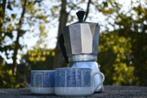 Closeup shot of a coffee percolator near two cups in the outdoor