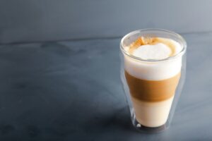 Perfectly gradient latte macchiato view over grey backdrop with copy space.